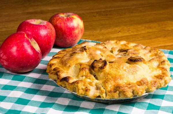 Apple pie and apples on checked cloth — Stock Photo, Image