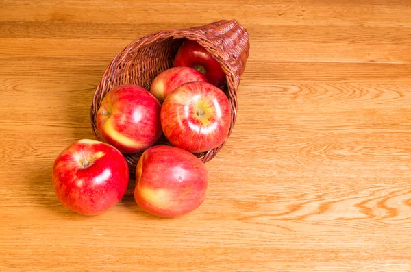 Red apples on table in cornucopia — Stock Photo, Image