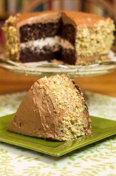 Fatia de bolo de chocolate com bolo no fundo — Fotografia de Stock