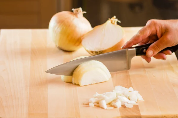 Koch schneidet Zwiebeln auf Schneidebrett — Stockfoto