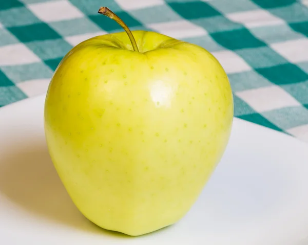 Золотое яблоко на белой тарелке — стоковое фото