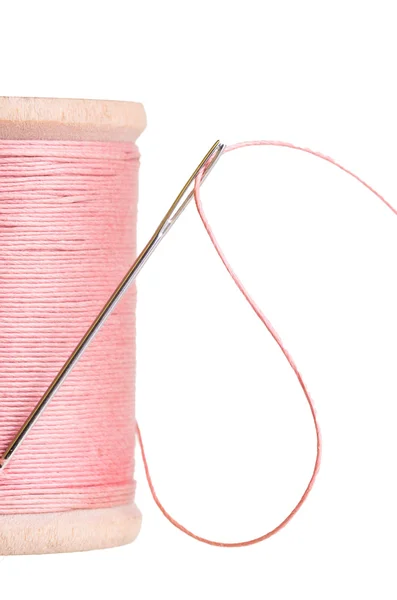 Катушка розовой нитки с иглой — стоковое фото