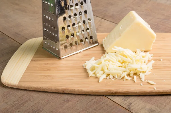 Сыр пармезан тертый на разделочной доске — стоковое фото