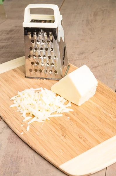 Сыр пармезан тертый на разделочной доске — стоковое фото
