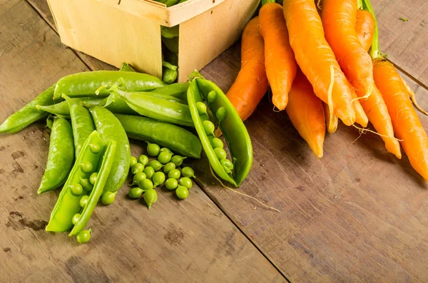 Frische geschälte grüne Erbsen und Karotten — Stockfoto