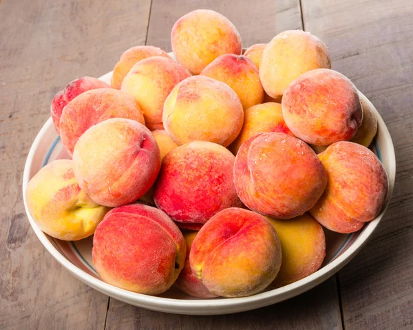 Skål med färska gula persikor — Stockfoto