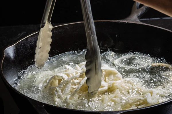 Cebolas sendo fritas em óleo quente na frigideira — Fotografia de Stock