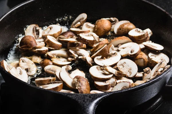 Sauteing gesneden champignons in een koekepan — Stockfoto