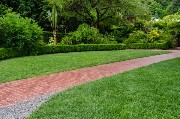 Brick walkway leading through a garden — Stock Photo, Image