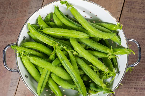 Fresh peas in a white colander — Stock Photo, Image