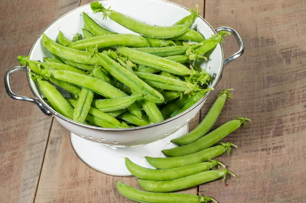 Fresh peas in a white colander — Stock Photo, Image