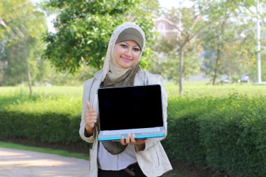 Genç Müslüman kadın başörtüsü gösterilen laptop ve yukarı