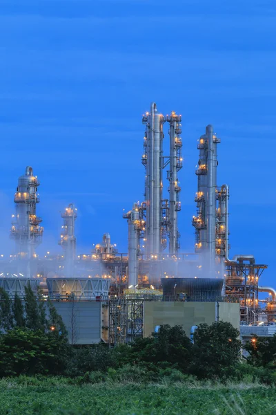Fábrica de refinería con campo verde en el crepúsculo —  Fotos de Stock