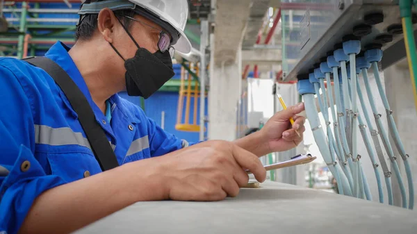 Industrial electrician wearing safety helmet Visual check electrical signal cable in industrial plant. safety concepts and working in industrial plants.