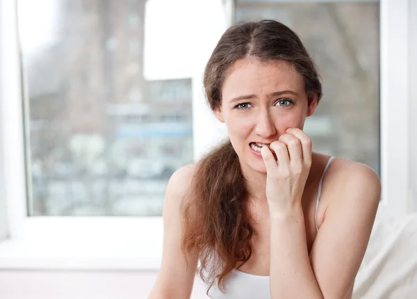 Portrait of a young girl with a funny face emotion, window in the background — Stock Photo, Image