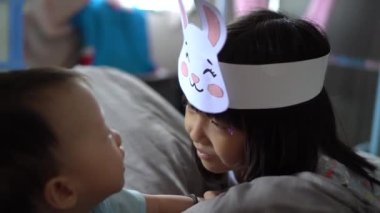 Kız kardeş tavşan şapkası tak ve küçük erkek kardeşiyle oyna.