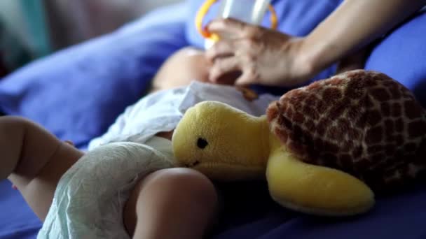 Bebisen Håller Foten Medan Han Dricker Mjölk Sköldpaddsleksak Vid Sängen — Stockvideo