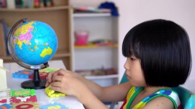 Küçük kızın elini kapat ve alfabe yapboz paspası oyna.