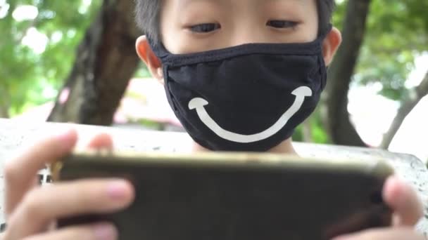 Een Klein Kind Houdt Handtelefoon Vast Het Glimlachende Gezichtsmasker Aan — Stockvideo