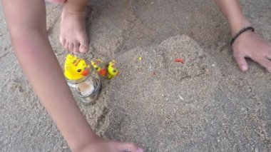 Yavaş çekim kızı kumsalın yanındaki plastik ördekle kumsalda oynar..