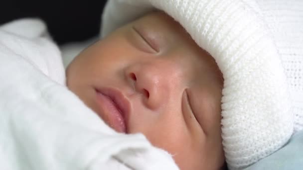 白い帽子と毛布の中で新生児の睡眠の顔を閉じます — ストック動画