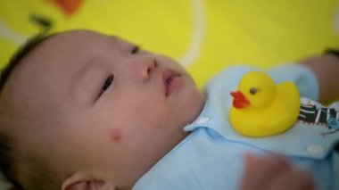 Bebek vücudunda plastik ördek oyuncağıyla dolaşır.