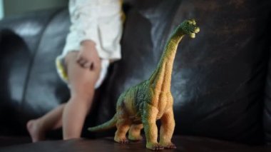 Seçici odaklı dinozor brachiosaurus oyuncağı heyecanlı erkek bebek tarafından tutulur.