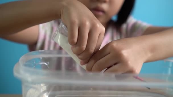 一个孩子倒入乳酸钙 和水混合 然后在玩神奇的水玩具之前搅拌 — 图库视频影像