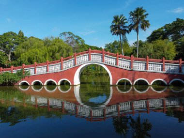 Kızıl Çin tarzı kırmızı geleneksel köprü. Gölün kenarında, Blus gökyüzünün altında.