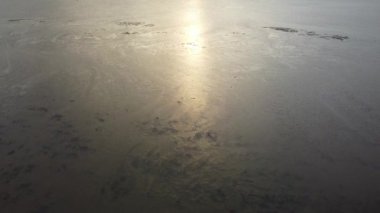 Hava manzarası gün batımında sahilin yakınındaki çamura bakıyor.