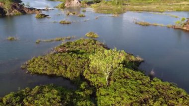 Hava yükseliyor ve terk edilmiş maden gölündeki adaya bakıyor.