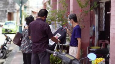 Georgetown, Penang, Malezya - 19 Kasım 2021: Yüzü maskeli turist, sokakta satıcı ile t-shirt indirimi.