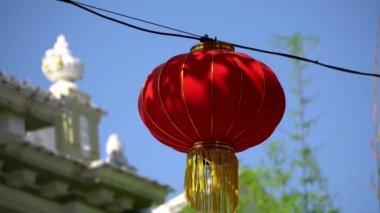 Mavi güneşli bir günde rüzgârdan esintiye çıkan kırmızı fener. Arkaplan eski binanın bulanık odak noktası.