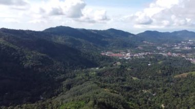 Balik Pulau yakınlarındaki yeşil tepenin üzerinden uçuyorlar.