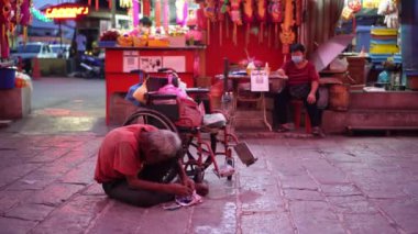 Ayer Itam, Penang, Malezya - 31 Ocak 2022: Tekerlekli sandalyede oturan yaşlı bir adam bağış bekliyor