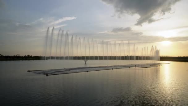 Venkovní vodní fontána u jezera při západu slunce