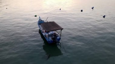 Mavi balıkçı teknesi gün ışığında kalır ve suyu yansıtır.