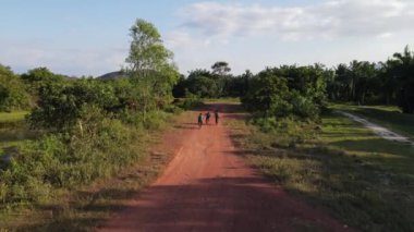 Akşam güneşi altında kırmızı kırsal yolda çocukların bisikletini takip et.