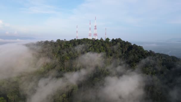 霧の低い雲の上の丘の頂上にある4つの通信塔への空中移動 — ストック動画