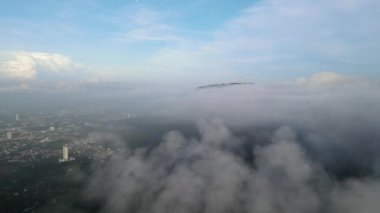 Hava manzarası, yerleşim yerinin yanındaki ormanda sisli bulutların üzerinde hareket eder.