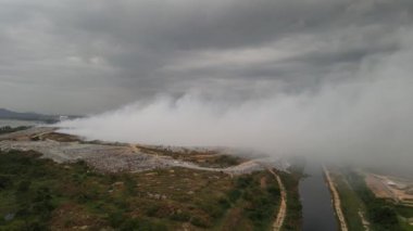 Çöp sahasının sulak arazisinde hava manzaralı yangın yangını. Büyük ölçekte duman havaya karışır.