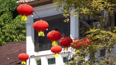 Yeşil ağacın yanındaki kırmızı fener ve eski bina.