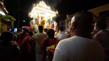 Bukit Mertajam, Penang, Malezya - 18 Aralık 2022: Yüzü maskeli bir adam gece at arabasının geçişi sırasında tabakta adak taşıyor