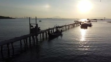 Georgetown, Penang, Malezya - 10 Ocak 2022: Siluet hava balıkçısı ahşap iskeleden balık tutmaya hazırlan