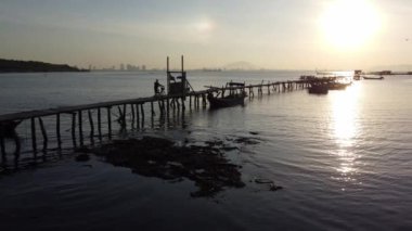 Jelutong, Penang, Malezya - 10 Ocak 2022: Balıkçı iskelesinin siluet ahşap köprüsüne doğru yavaşça ilerleyin