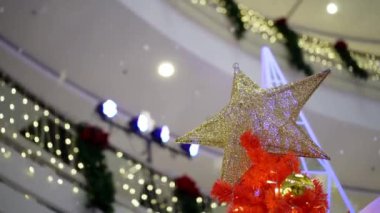 Select focus Star shape ornament on red. Background is fake snow drop from ceiling
