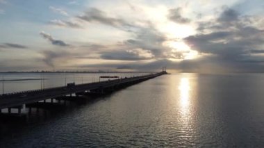Batu Uban, Penang, Malaysia - Oct 23 2021: Aerial move in silhouette boat at sea and car traffic at Penang Bridge