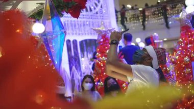 Georgetown, Penang, Malaysia - Dec 24 2021: Indian man with face mask capture photo of ornament Christmas with mobile phone
