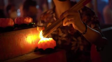 Select focus the hand hold the incense stick and burn with lotus candle in night at Chines temple in night