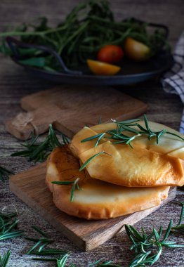 Tahtada tütsülenmiş Provola madalyonları otlar ve baharatlarla kesilmiş.